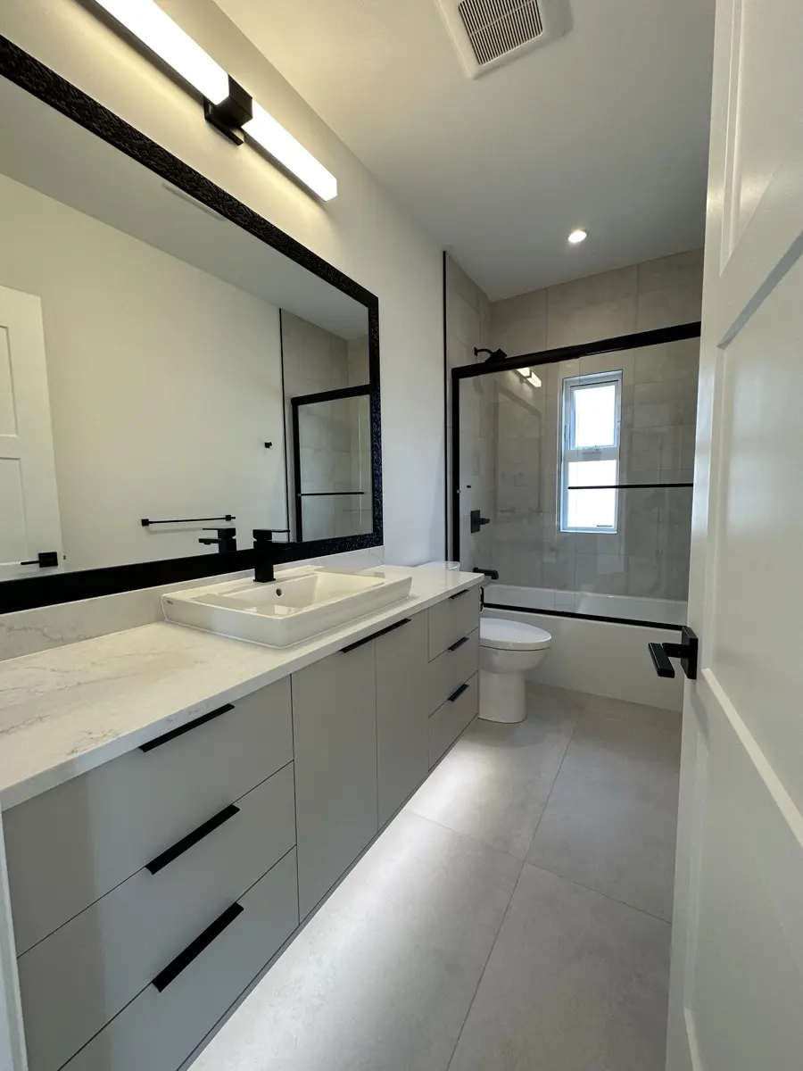 Main bath with a long vanity and black-framed mirror