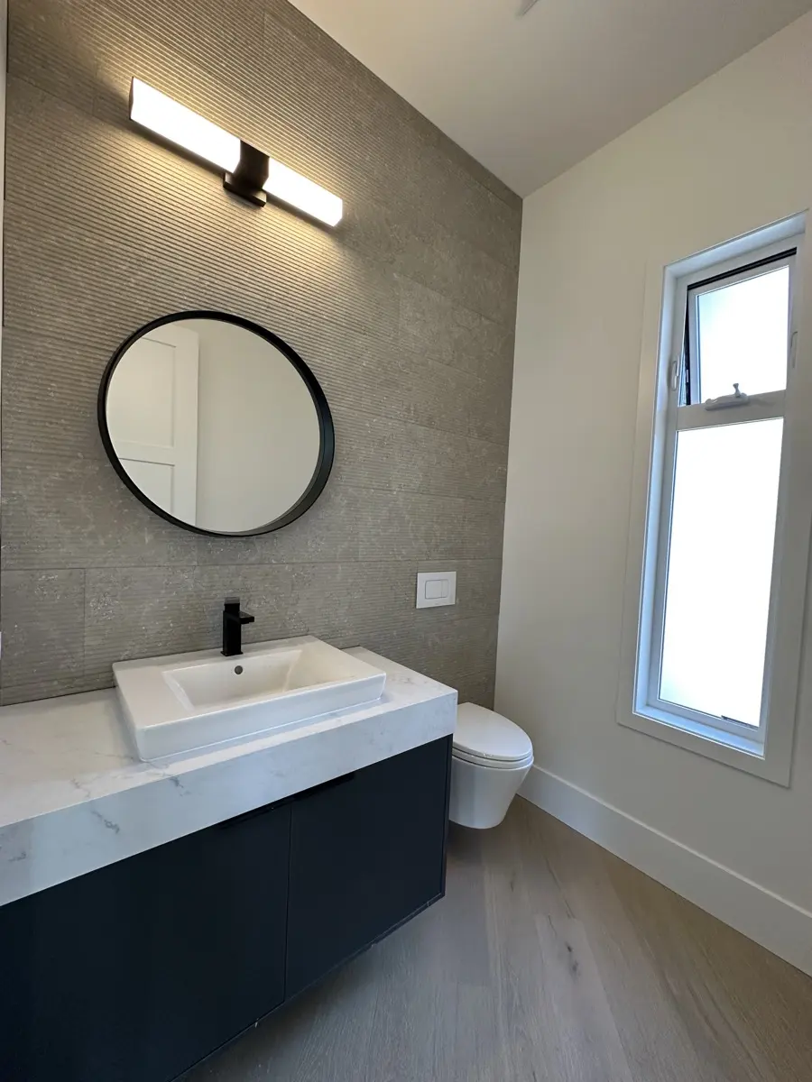 Powder room with a fluted stone feature wall and round black mirror